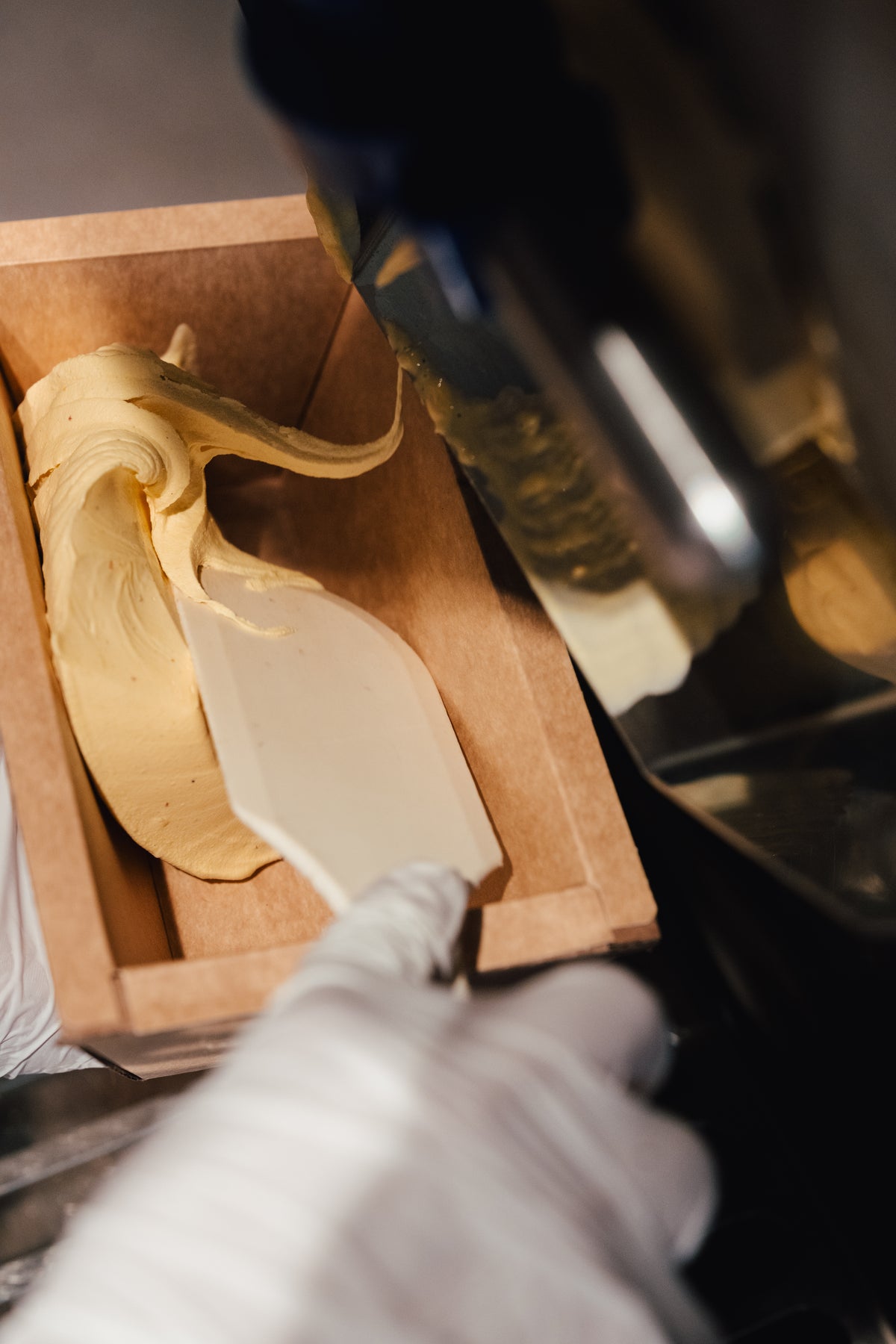 Eis wird in der Kartonbox mit dem Spachtel glattgestrichen